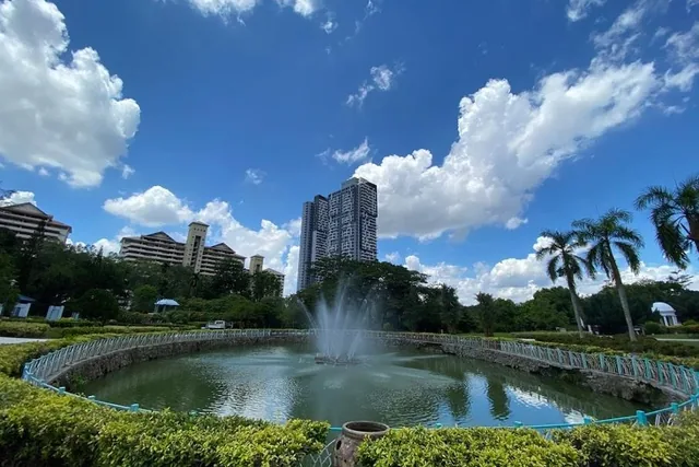 The fountain pond in Bukit Jalil Recreational Park, with palms and homes behind