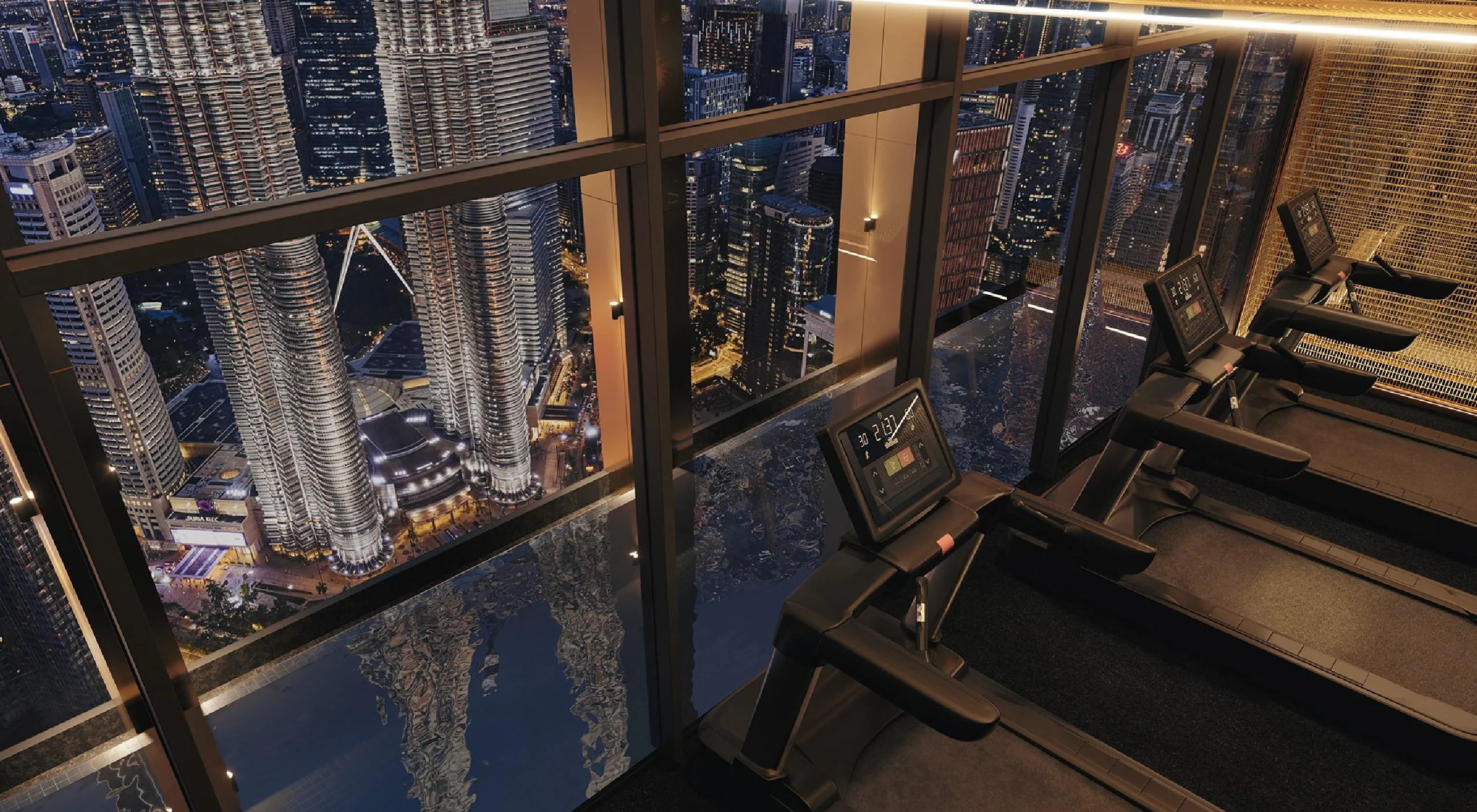The gym on Level 80 of Divine KLCC, overlooking the Petronas Twin Towers at night