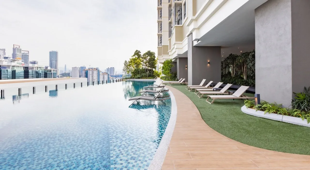 The garden pool and loungers on Level 5 of Laurel Residence, with the city skyline beyond