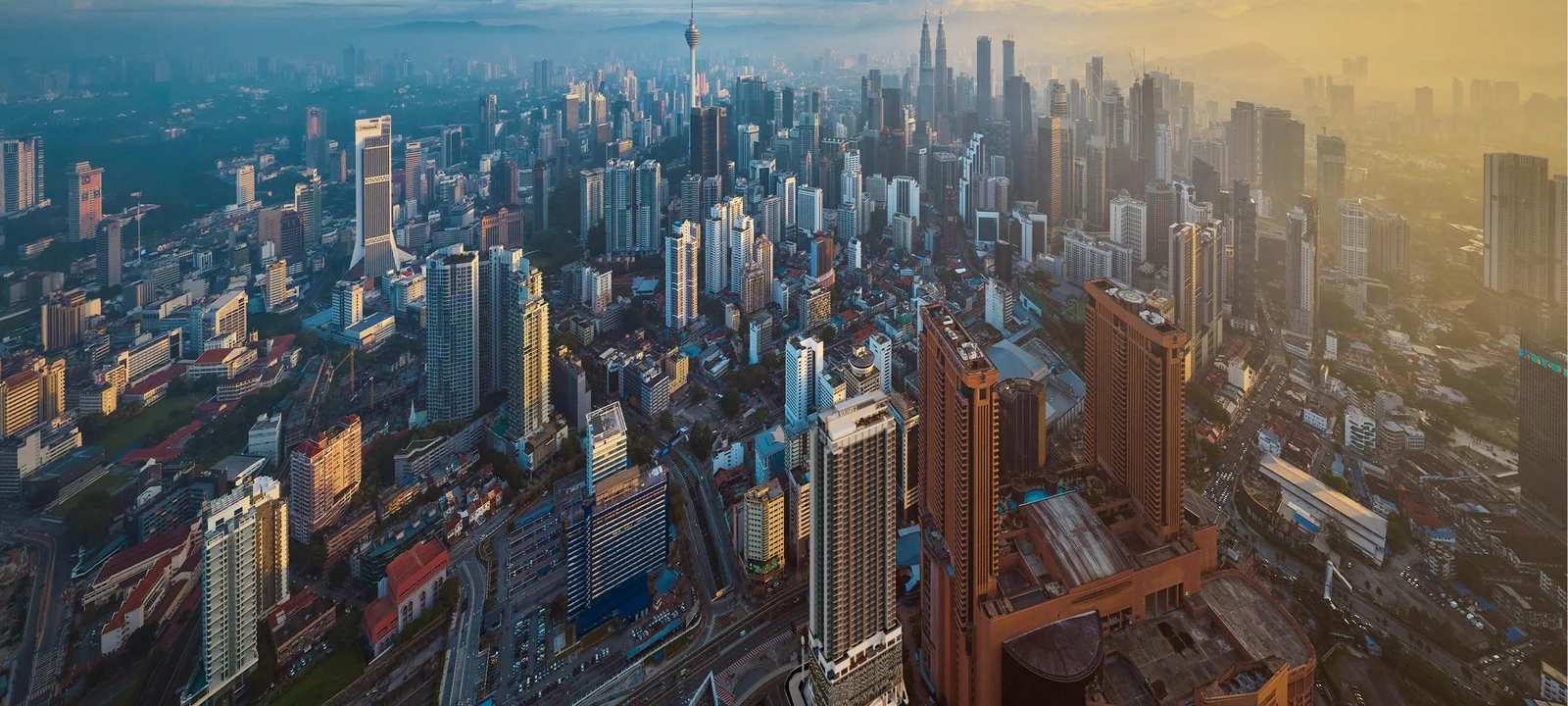 The Kuala Lumpur skyline from above at sunrise, with the Petronas Twin Towers in the distance, artist's impression