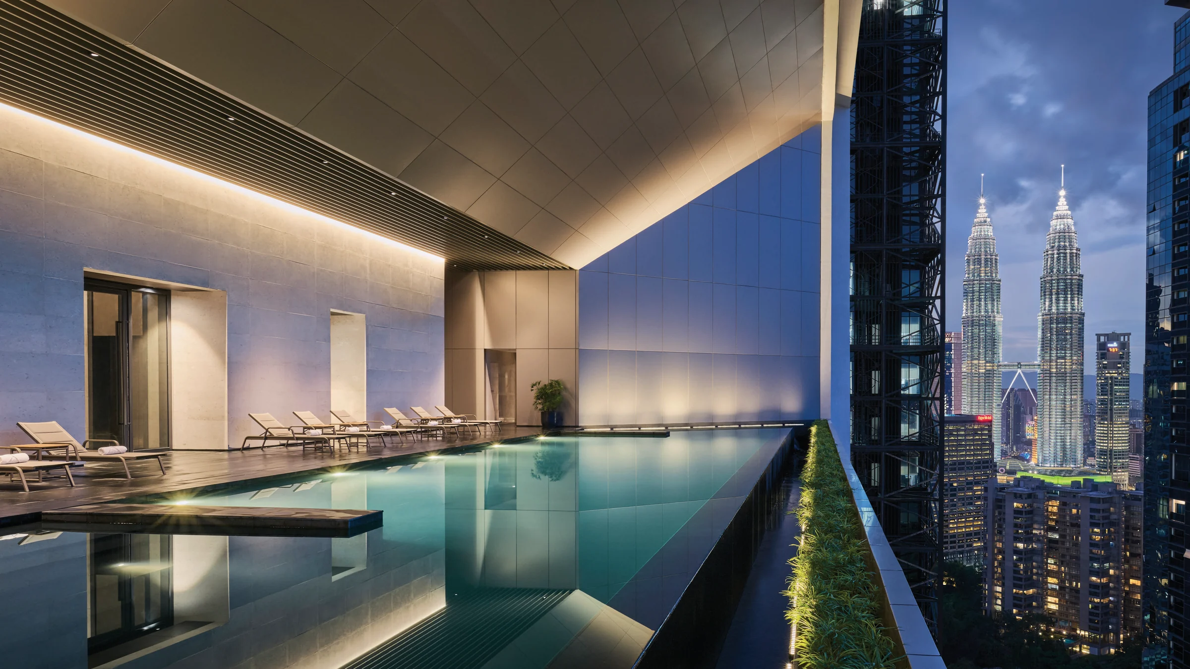 The Conlay heated infinity pool at dusk, with the Petronas Twin Towers beyond