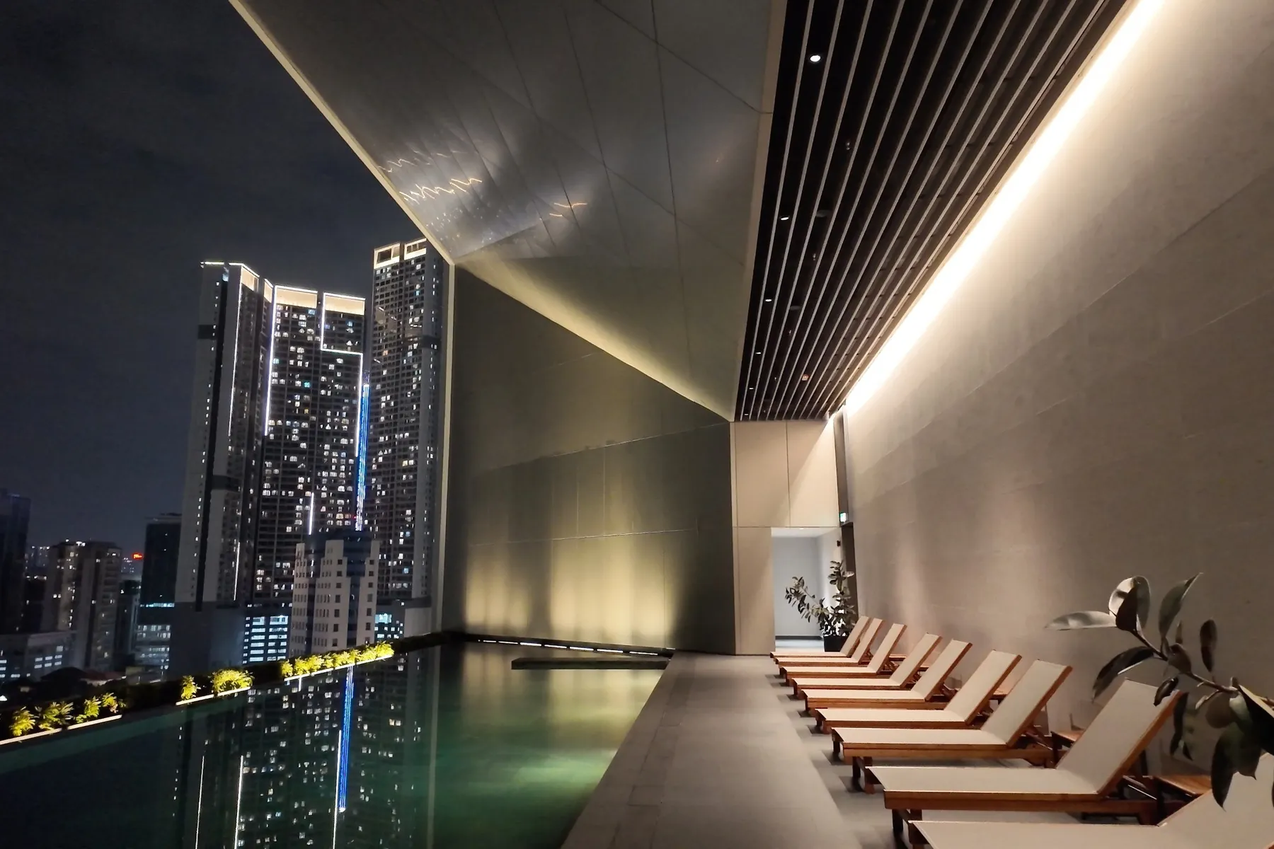 The Conlay sky pool and sun loungers at night, with the KL skyline