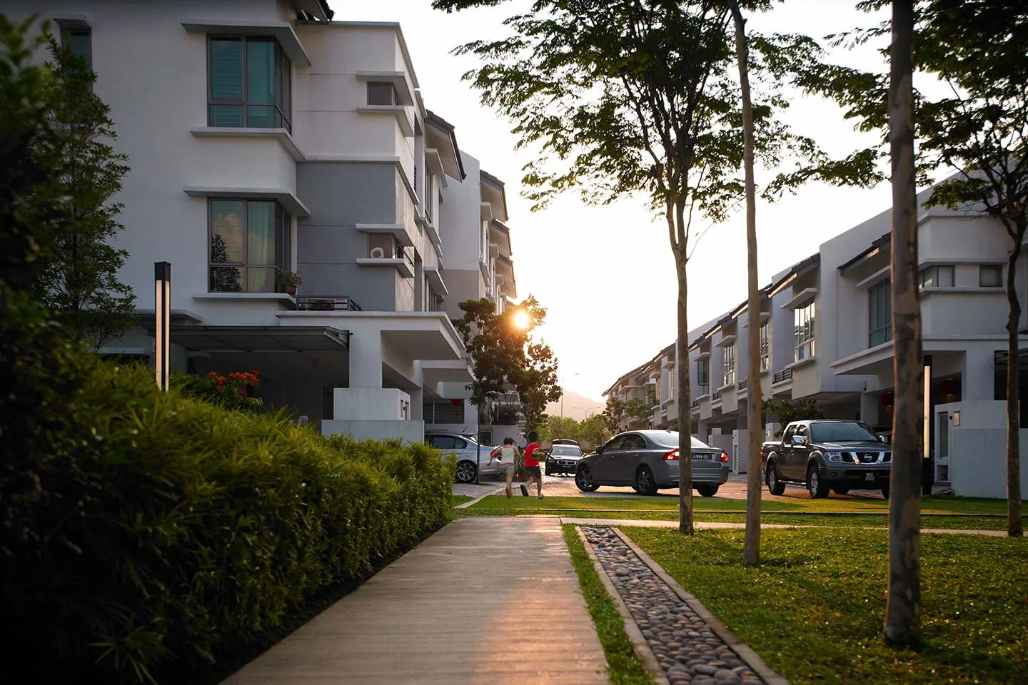 Children playing on a tree-lined street of three-storey homes at Desa ParkCity, the concept Zenia follows